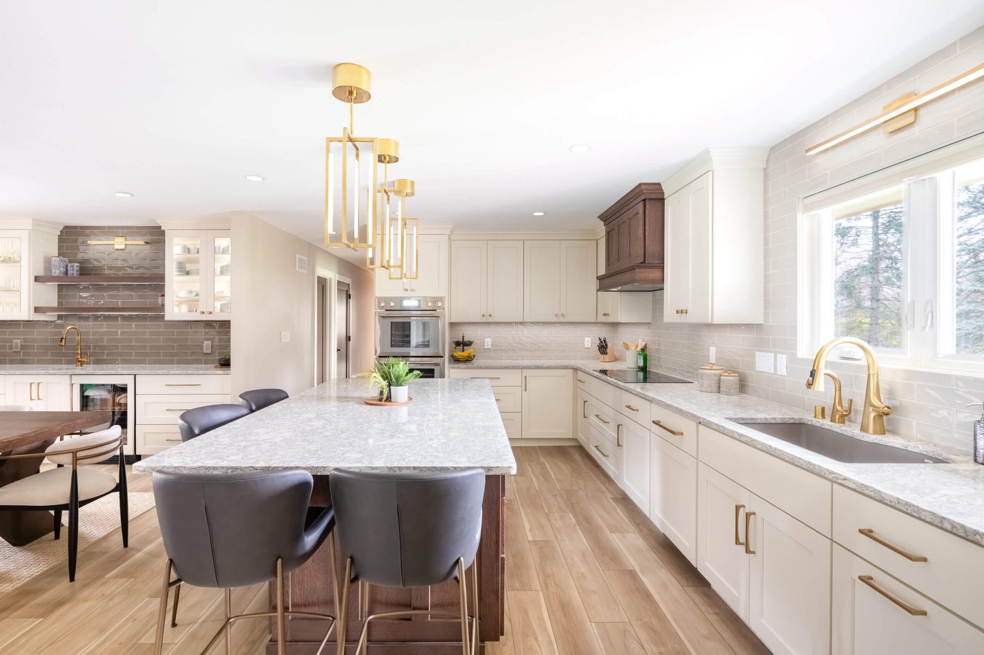 Open-concept kitchen remodel with brass pendants by Advantage Design + Remodel