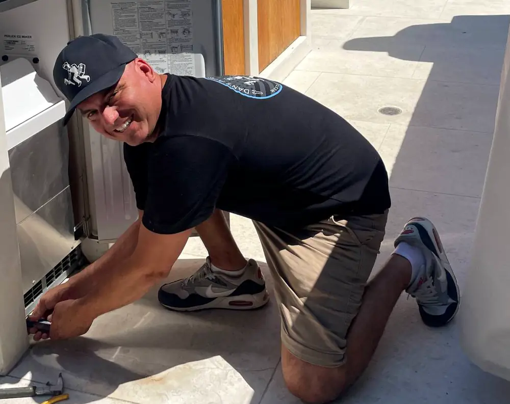 Danny kneeling to fit an ice maker into an outdoor kitchen