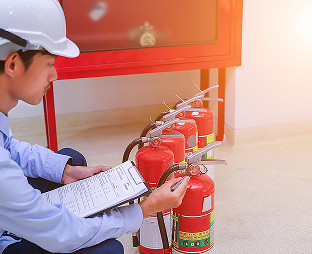 Technician inspecting portable fire extinguishers with a checklist