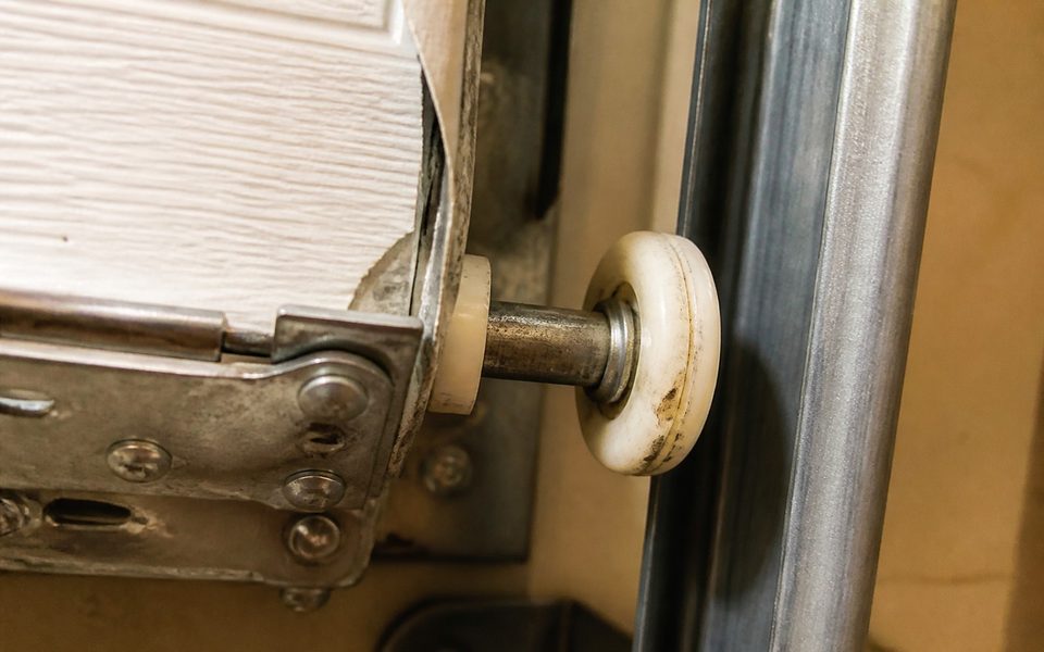 Worn garage door roller and hinge plate that causes a noisy garage door