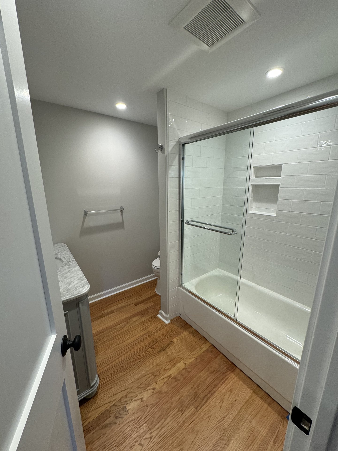 Renovated bathroom with a tiled tub surround and glass sliding doors