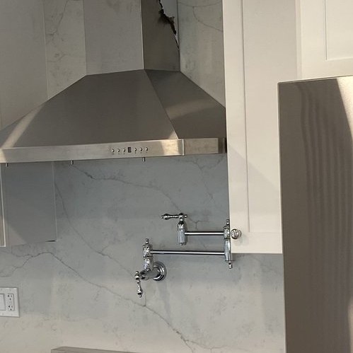 Marble slab backsplash behind a range with a wall-mounted pot filler