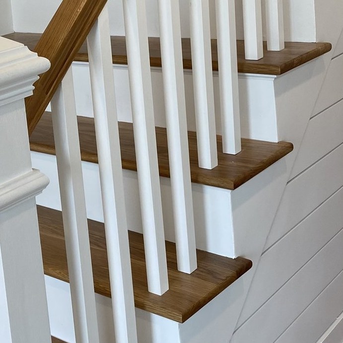 White oak stair treads with painted risers and balusters against shiplap