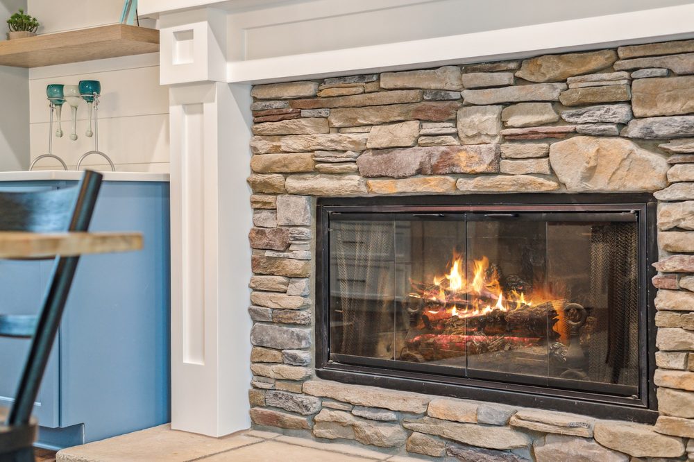 Finished basement with stone fireplace by Momentum Construction