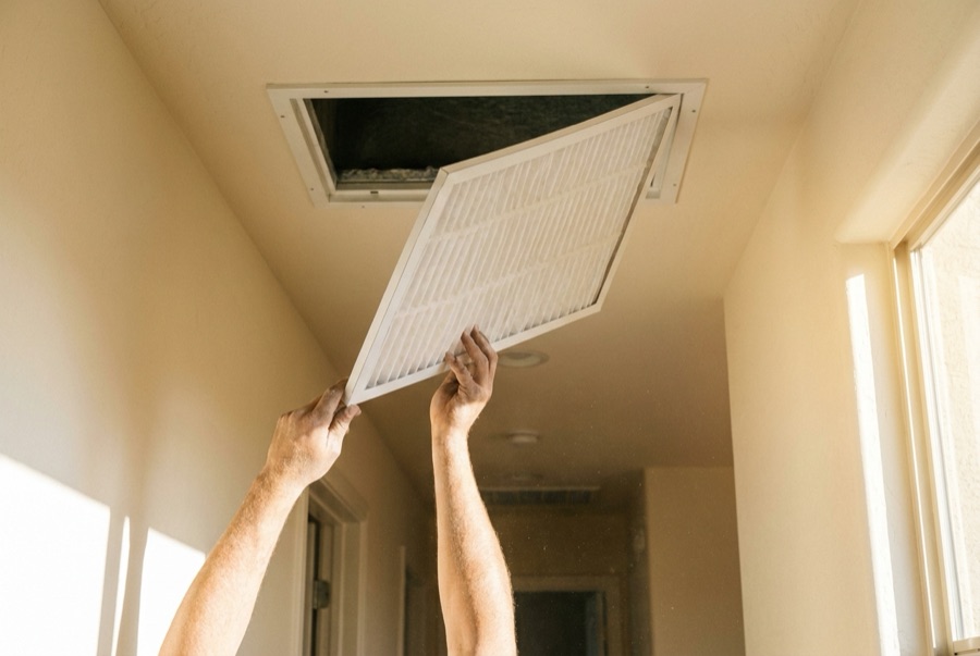 Fresh air filter being installed in a sunlit Arizona hallway return vent