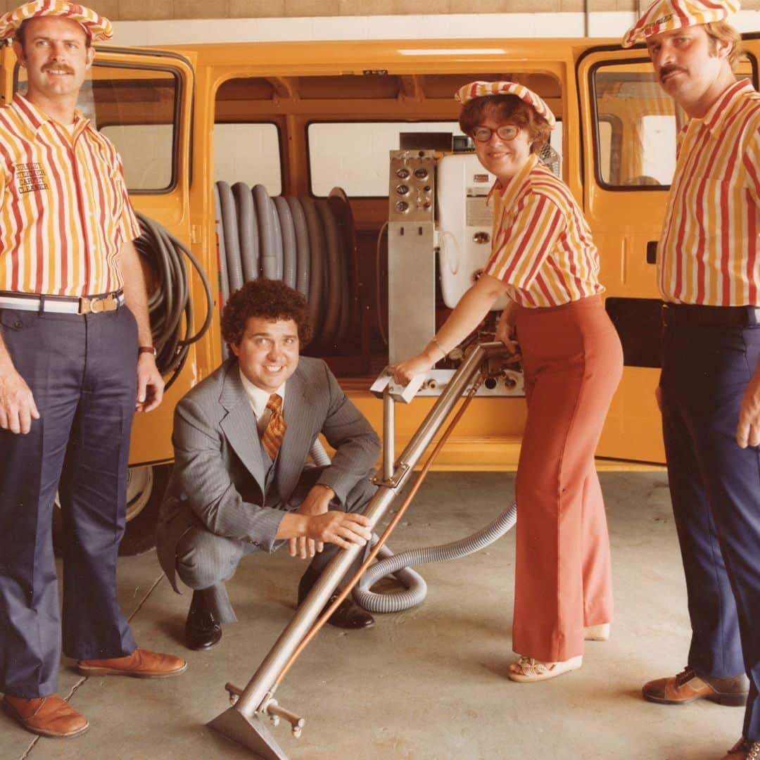 Stanley Steemer crew with a yellow service van in the 1970s