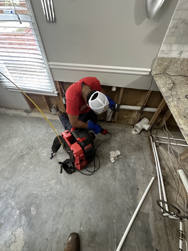 Technician cleaning a kitchen drain line